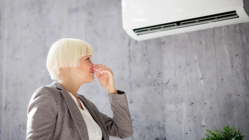 woman holding her nose because air conditioner smells bad