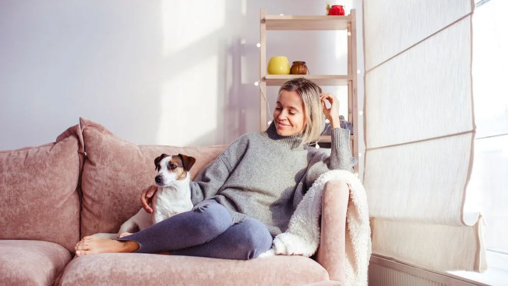 woman and dog sitting in living room enjoying a cozy day in winter