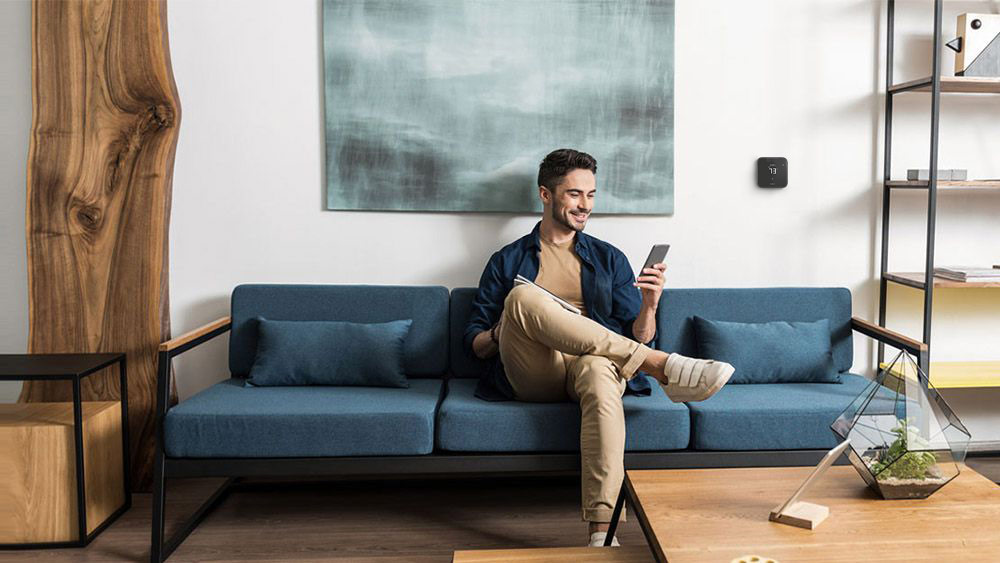 A person using cielo home app to adjust their room temperature. Breez Max - a smart thermostat for mini-splits, installed on the wall 