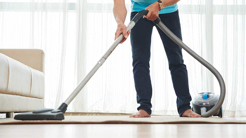 Man cleaning the room with a vacuum. 