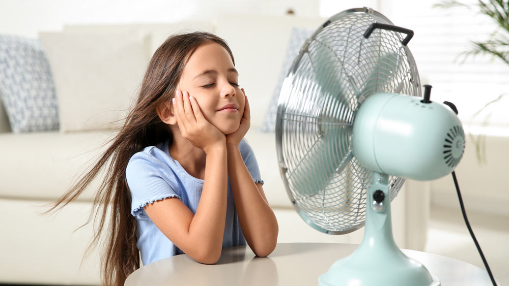 Girl sitting in front of a portable fan