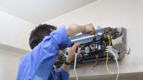 An HVAC techician performing AC repairs