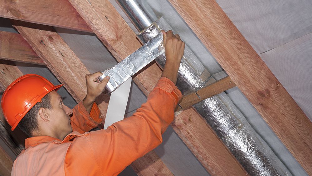 An HVAC technician installing high velocity HVAC system in the ceiling 