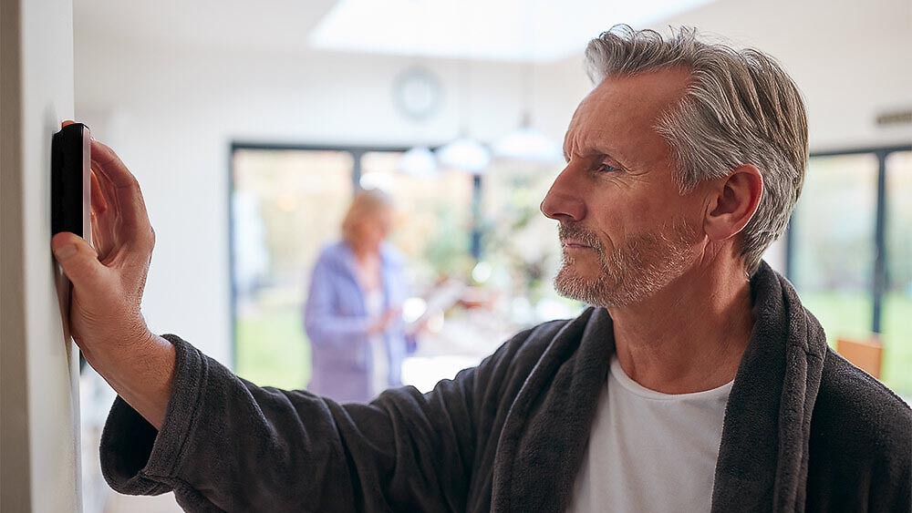 a man using a smart thermostat in a living room for central heating