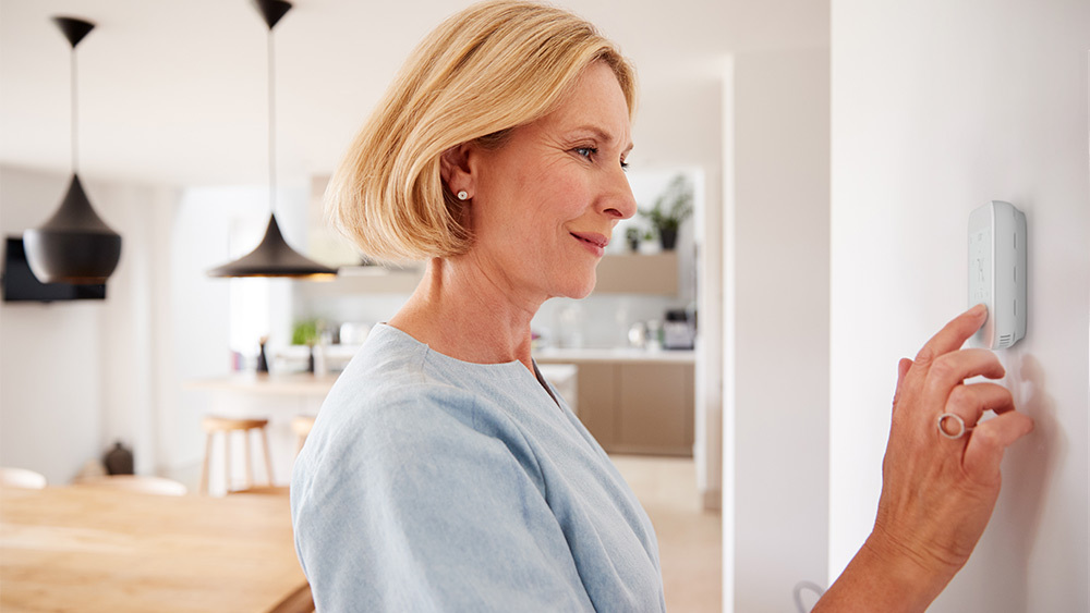 Old lady changing temperature settings on her smart thermostat