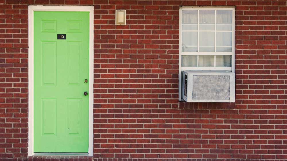 window AC installed in a red walled house with a parrot green door