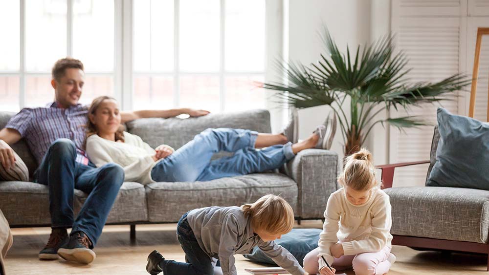 Two children are playing while their parents are relaxing nearby 