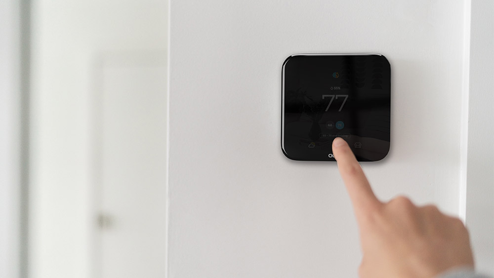 A person adjusting temperature on smart thermostat