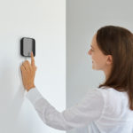 A woman adjusting temperature on smart thermostat