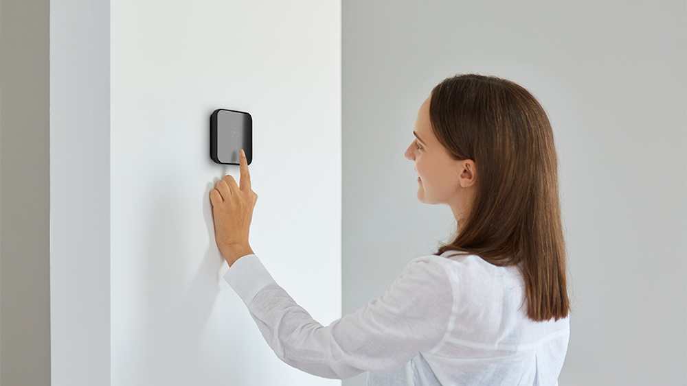  A woman adjusting temperature on smart thermostat 