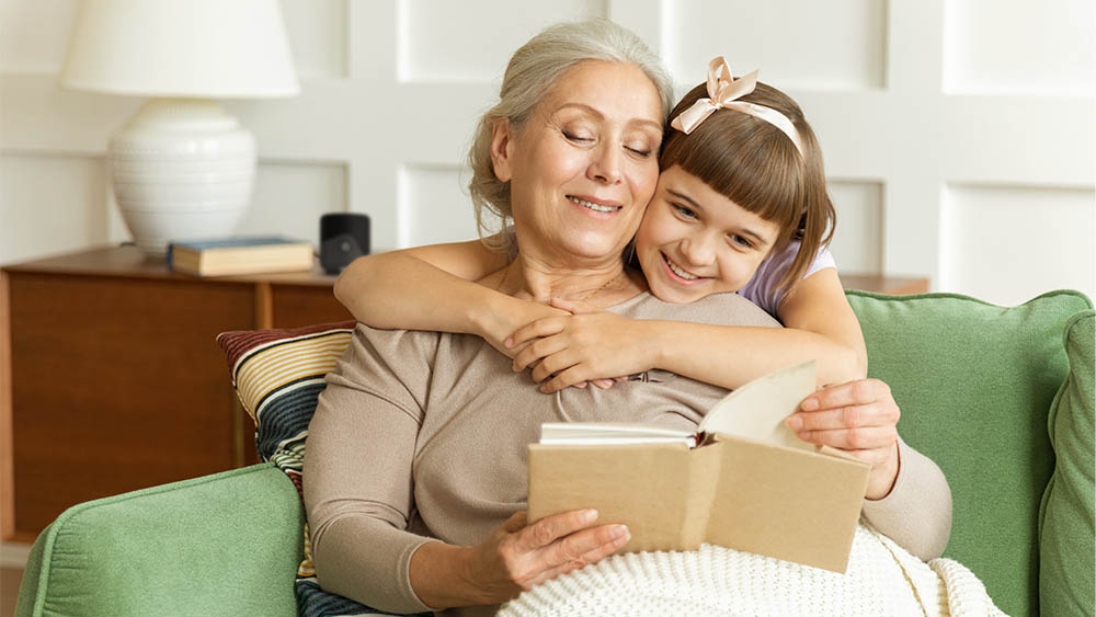 Grandmother and granddaughter reading in a comfy room with a Cielo device in the back