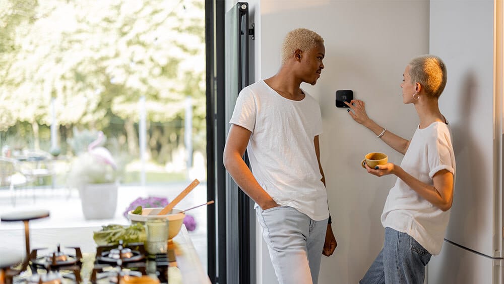 Man standing next to a person reprogramming a thermostat