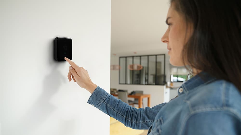 Woman making tmperature adjustments on her smart thermostat