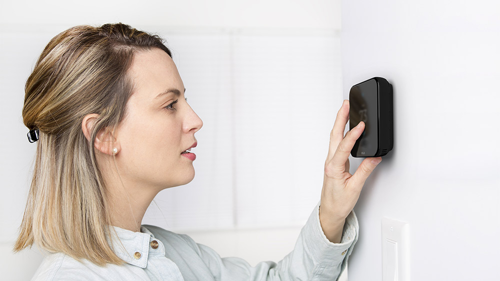 A woman is adjusting temeprature on her smart thermostat