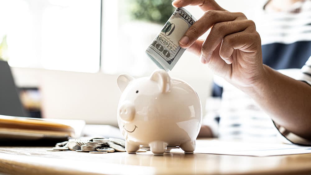 Person putting money into a piggy bank