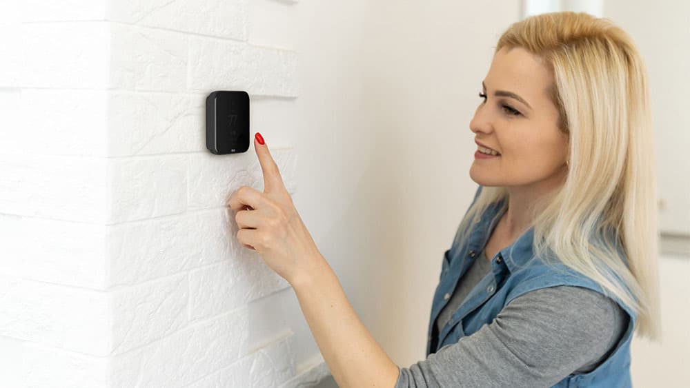 Woman using smart thermostat