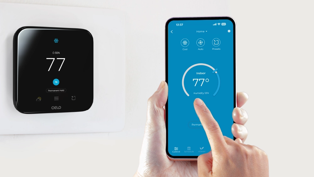 a person using cielo home app. Cielo smart thermostat can be seen in the background