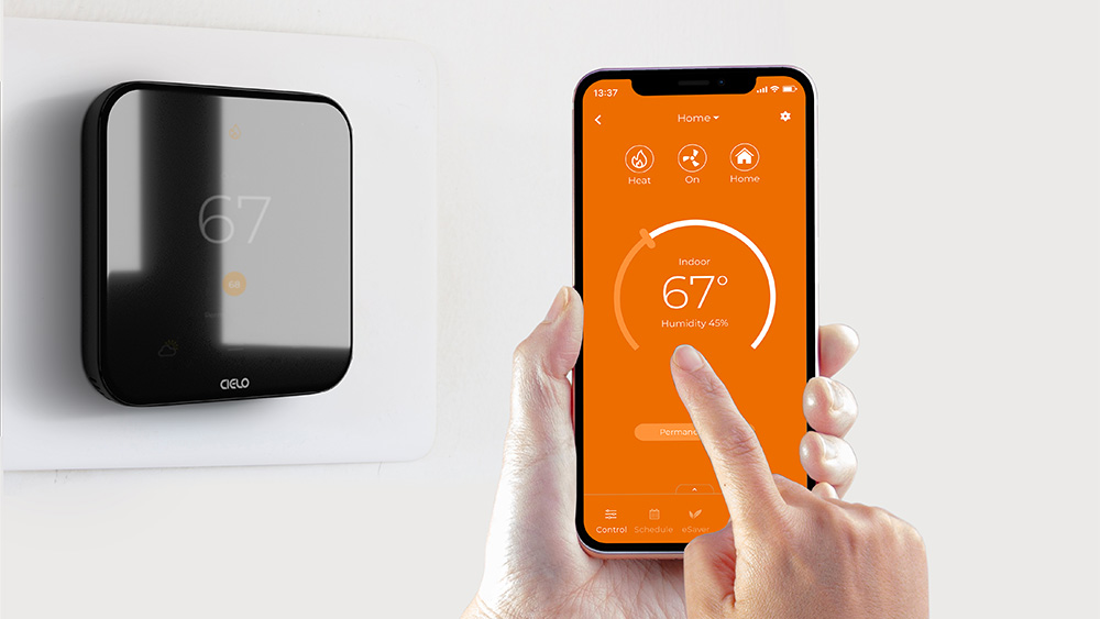 cielo smart thermostat installed on the wall. A person is using cielo mobile app to adjust the settings in heat mode 
