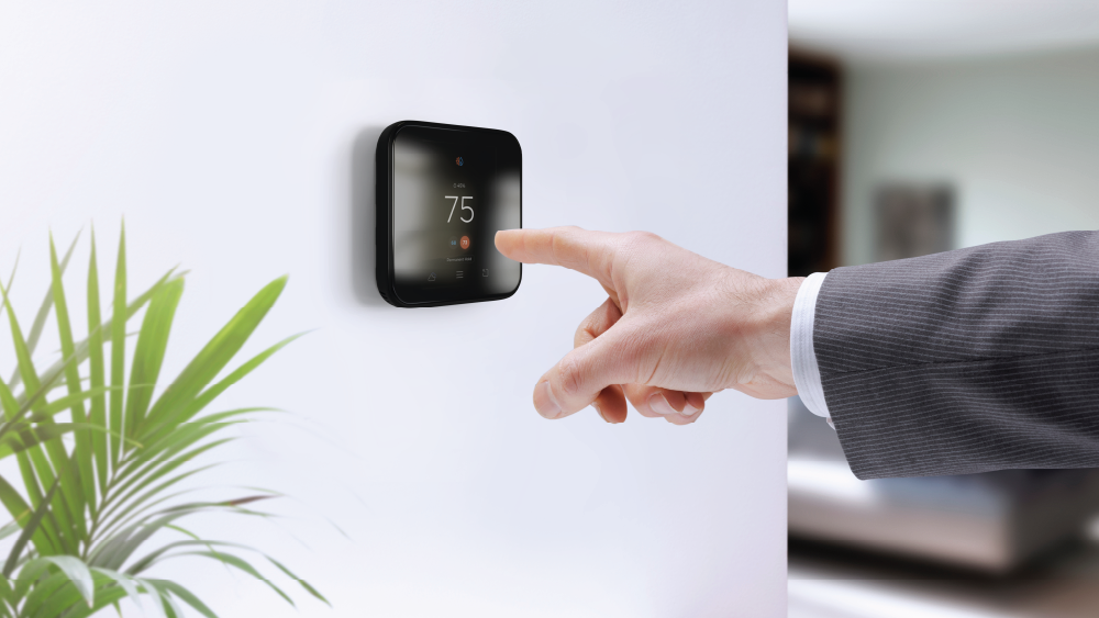 A man making temperature changes on his Cielo smart thermostat before heading out