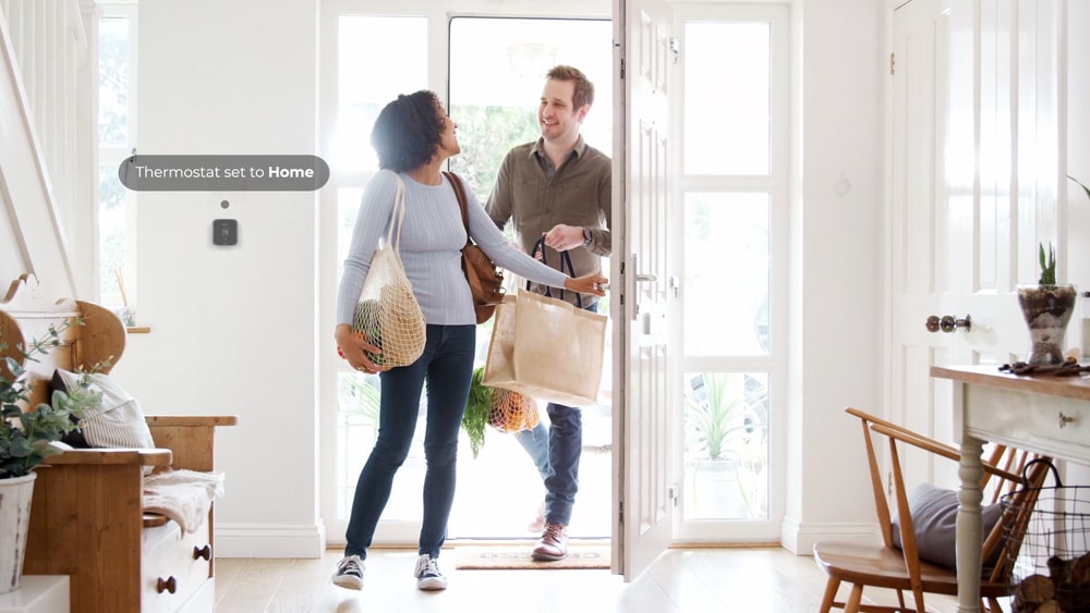 Cielo Smart Thermostat energy savings with geofencing as couple comes home holding grocery bags.