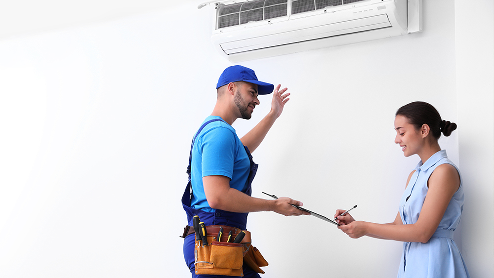 Professional technician speaking with woman about air conditioner
