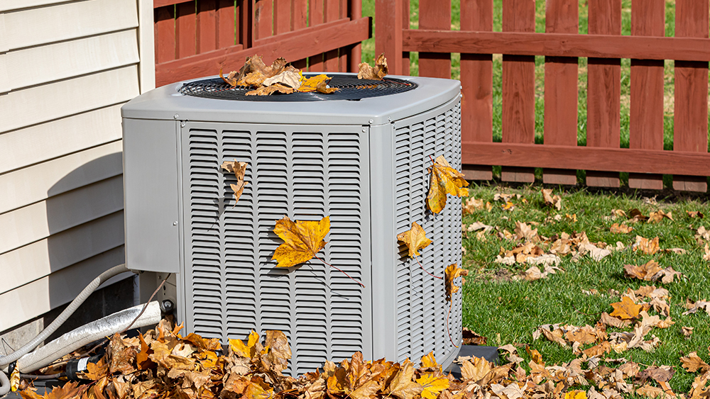 Dirty air conditioning unit covered in leaves. Cleaning the outdoor unit can help your AC work better 