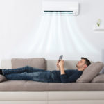 man using phone on sofa under air conditioner