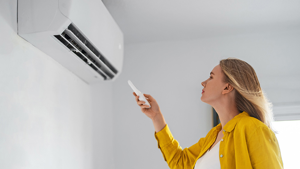 woman turning on air conditioner to cool the room 