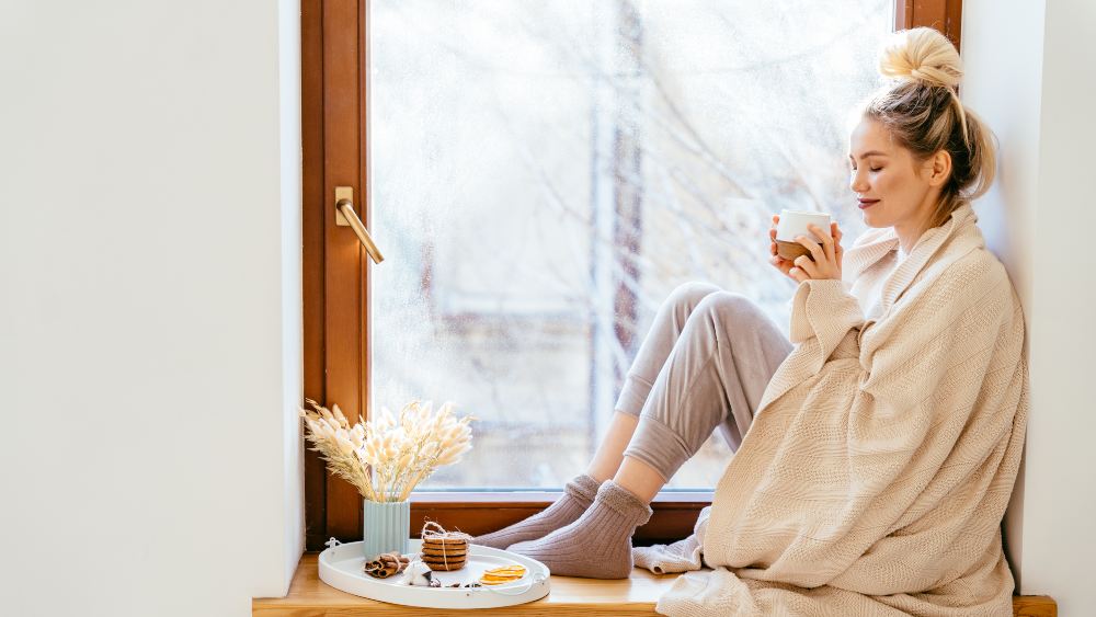 woman sitting, sipping her hot beverage in winter