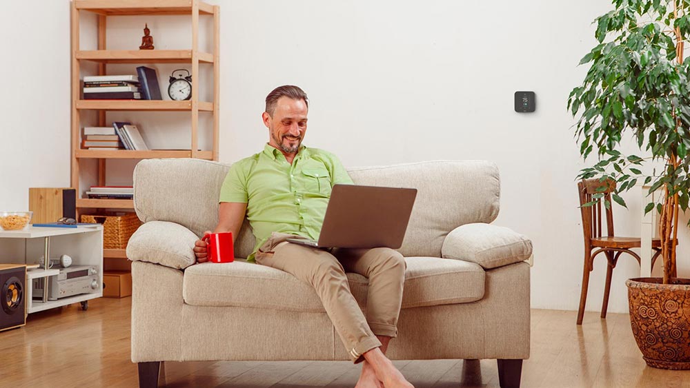 thermostat controlling HVAC system as man relaxes