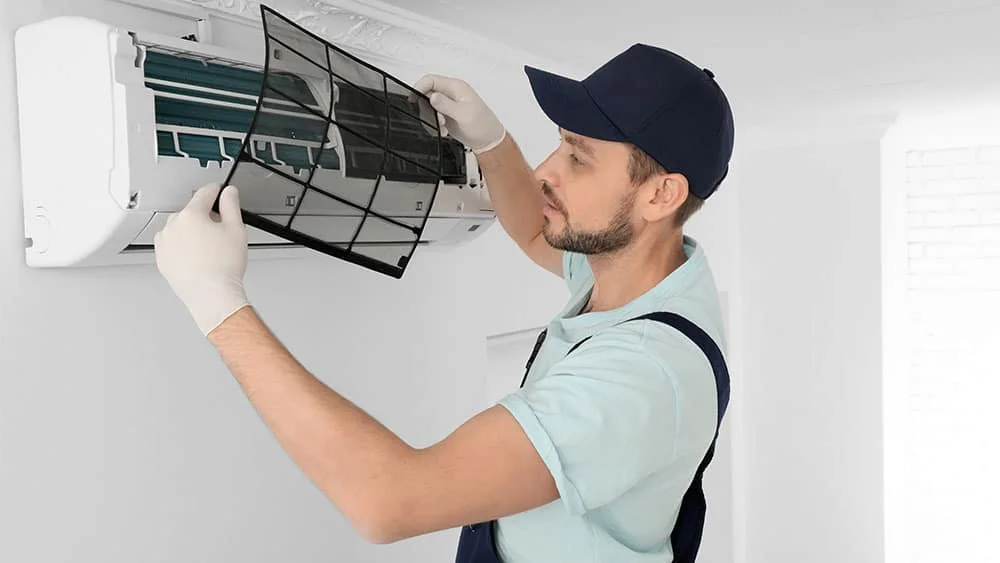 A technician cleaning the indoor mini-split unit 