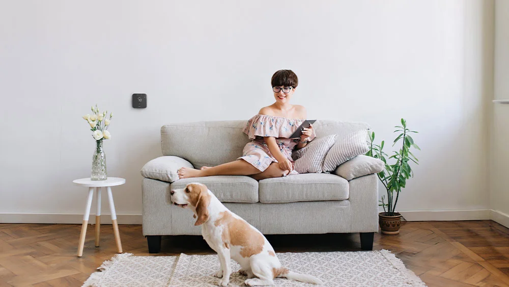 A woman sitting in her living room with her dog while Breez Max maintains a perfect room temperature.