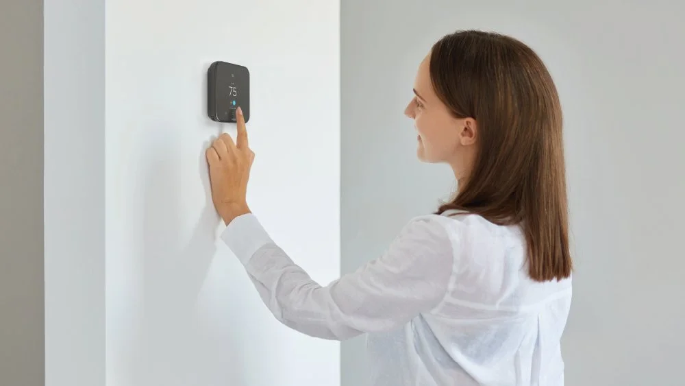 a woman adjusting temperature on cielo smart thermostat